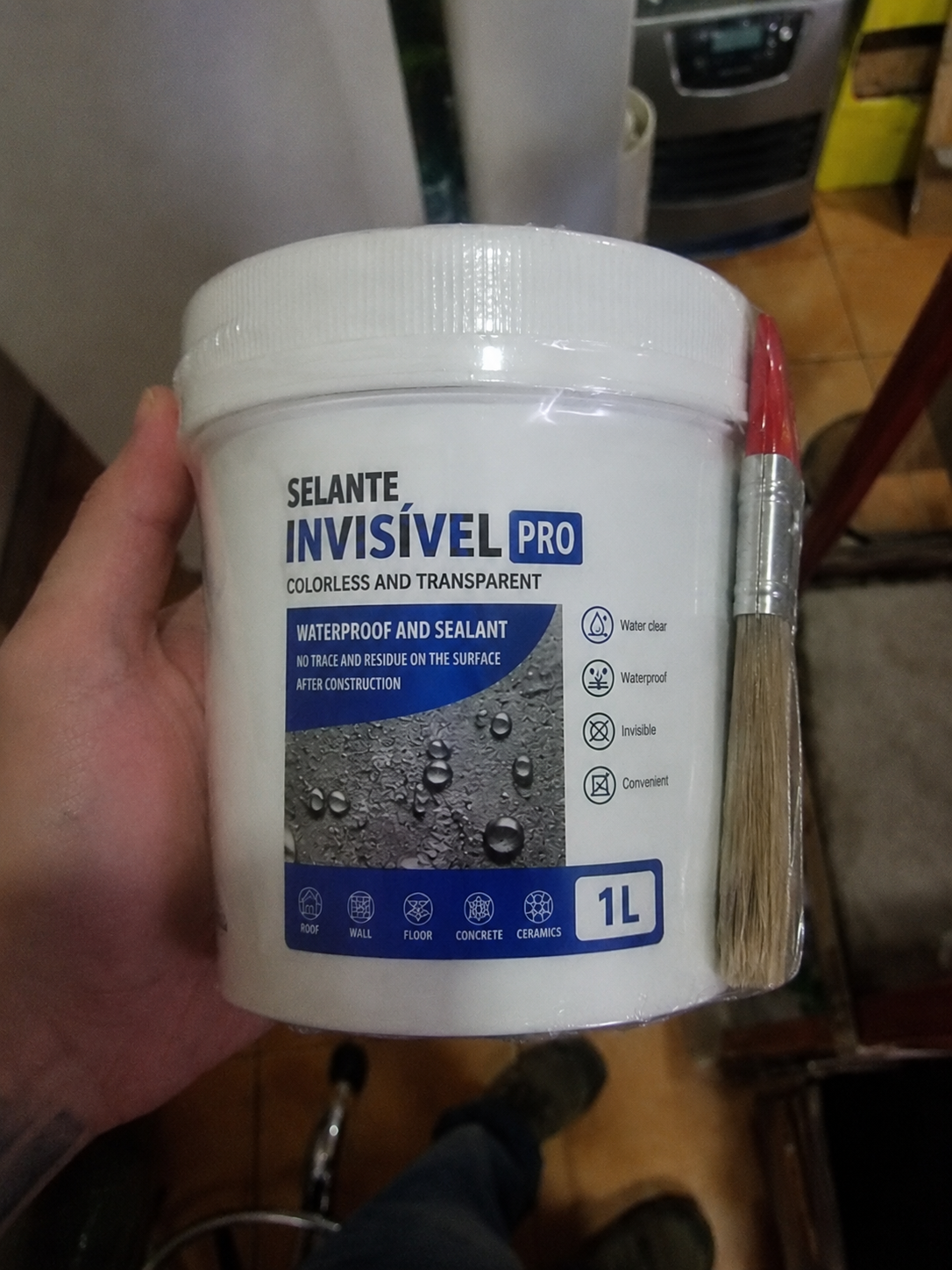 Cliente segurando o balde de 1L do Selante Invisível PRO com pincel vermelho, mostrando a embalagem lacrada